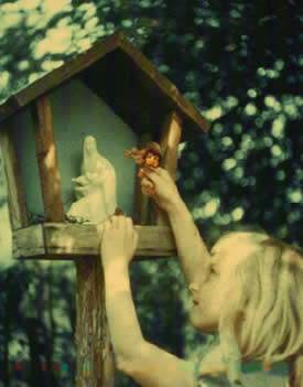 A child makes an offering to Our Lady at a wayside shrine