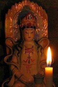 A candle on a shrine to Quan Yin